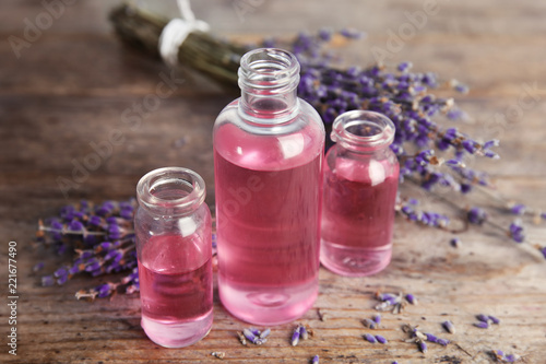 Fototapeta Naklejka Na Ścianę i Meble -  Bottles with aromatic lavender oil on wooden table