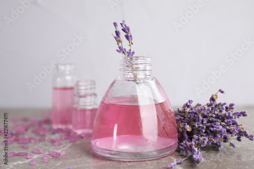 Fototapeta Naklejka Na Ścianę i Meble -  Bottles with aromatic lavender oil on grey table
