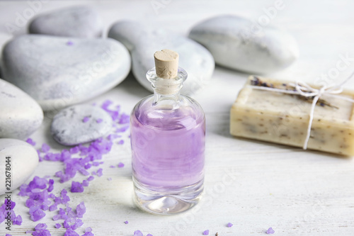 Fototapeta Naklejka Na Ścianę i Meble -  Bottle with natural herbal oil, soap and lavender flowers on wooden background