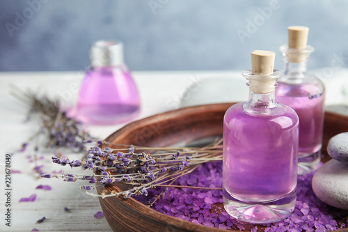Bottles with natural herbal oil and lavender flowers on wooden table
