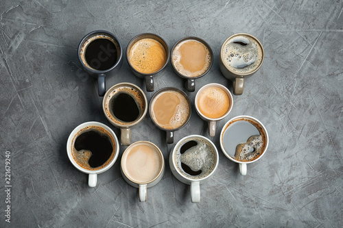 Many cups with tasty aromatic coffee on grey table, flat lay