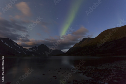 Aurora in the night sky cut the mountains  reflected in the water. Yamal. Russia