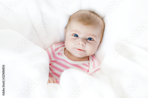 Cute adorable newborn baby in white bed on a blanket. New born child, little adorable girl looking surprised at the camera. Family, new life, childhood, beginning concept