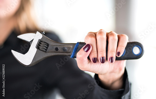 Gender roles and equality concept. Against and anti sexism, stereotypes and chauvinism. Feminism and female power. Confident and powerful woman holding tool, wrench, in hand. Female mechanic. photo