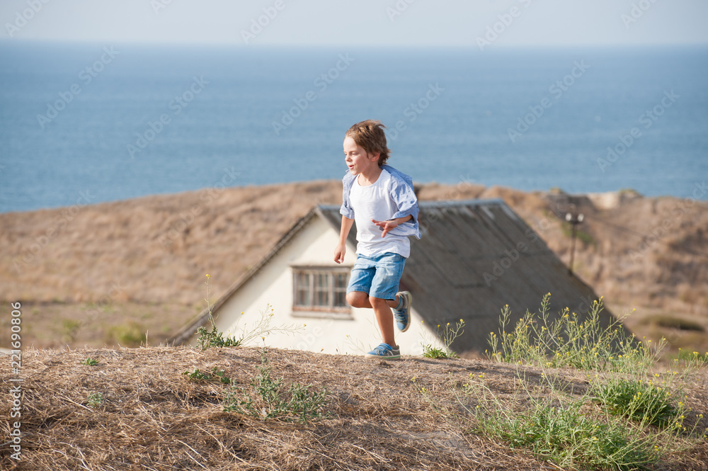 cute little boy running fast outdoors autumn sea and old house cute little boy running fast outdoors autumn sea and old house