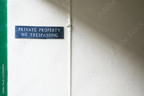 Fototapeta Naklejka Na Ścianę i Meble -  No trespassing private property sign on white wall at estate entrance