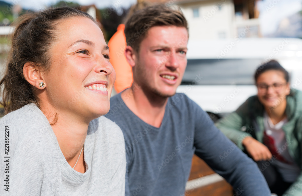 Fototapeta premium several young male and female people sitting on a bench and smiling and watching a game
