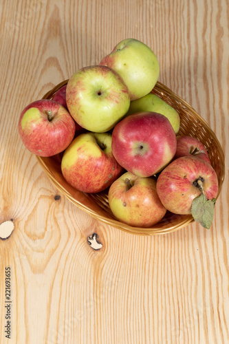 Basket full of ripe apples on a wooden table