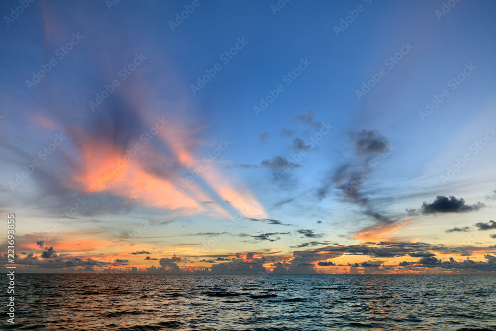 Abstract seascape panoramic sky background - Sunset colors with beautiful hues of blue, orange, purple pink and yellow. Calm seas/ocean in the bottom of the frame. Minimalistic simple background image
