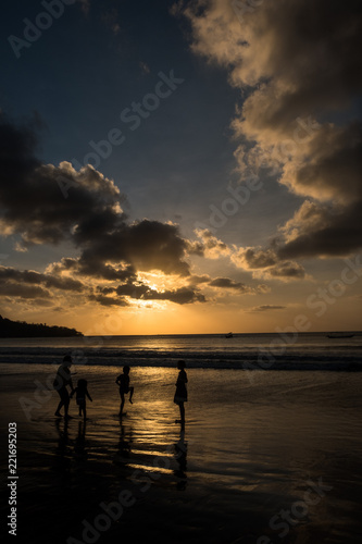 Kids playing in thh water at the beach at sunset