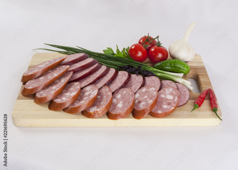 still life with sliced smoked sausage greens and tomatoes on a white background still life with sliced smoked sausage greens and tomatoes on a white background