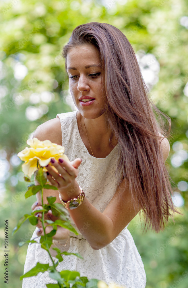 Young girl in a white dress in a summer park smelling a rose
Young girl in a white dress in a summer park smelling a rose