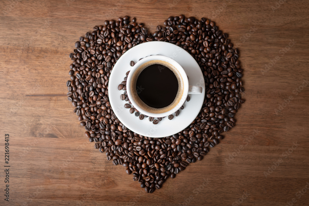 Hot coffee cup with heart pattern of roasted coffee beans Hot coffee cup with heart pattern of roasted coffee beans