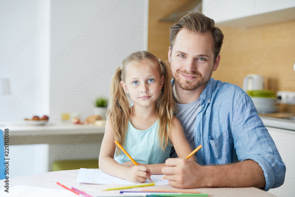 Young man and little girl with crayons siting in the kitchen at home, drawing and having rest on weekend Young man and little girl with crayons siting in the kitchen at home, drawing and having rest on weekend