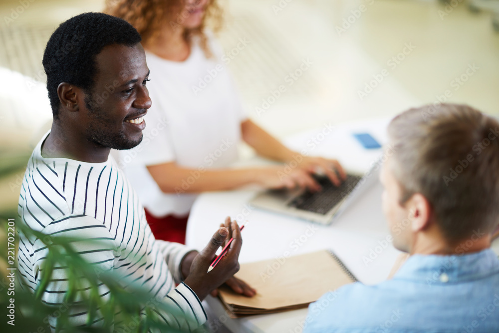 African-american guy consulting with one of his groupmates while preparing home assignment African-american guy consulting with one of his groupmates while preparing home assignment