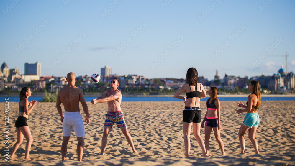 Beautiful young sports men and women playing volleyball in the evening Beautiful young sports men and women playing volleyball in the evening