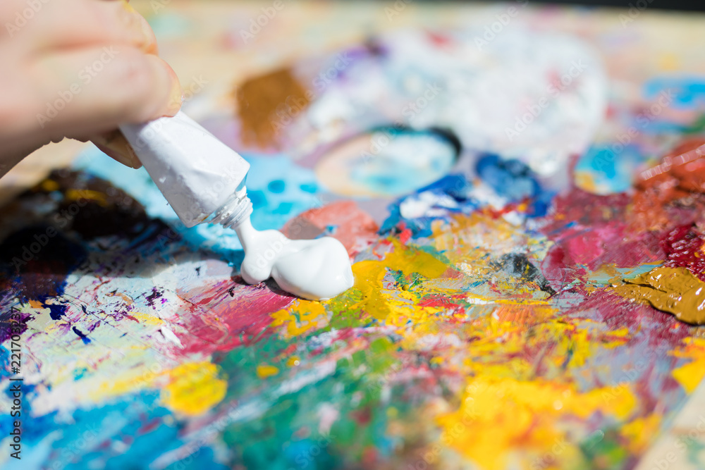 Fototapeta premium Artist or painter putting white gouache or paint on palette to mix it with other colors before painting