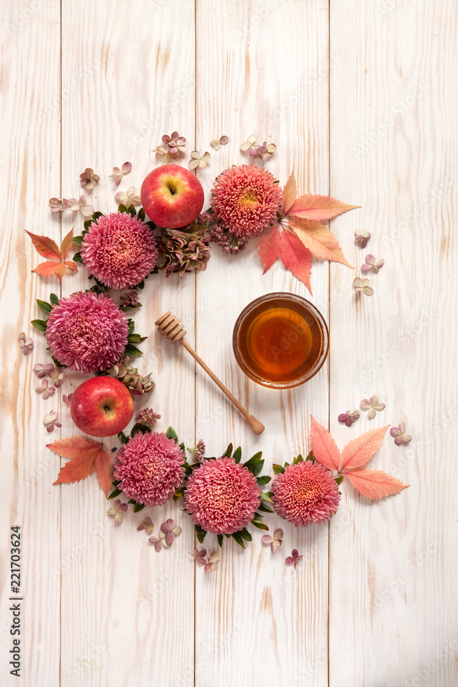Apples, pink flowers and  honey with copy space form a floral decoration. Concept for Rosh Hashanah the Jewish New Year, harvest festival, Lammas. Top view, close up on white wooden background