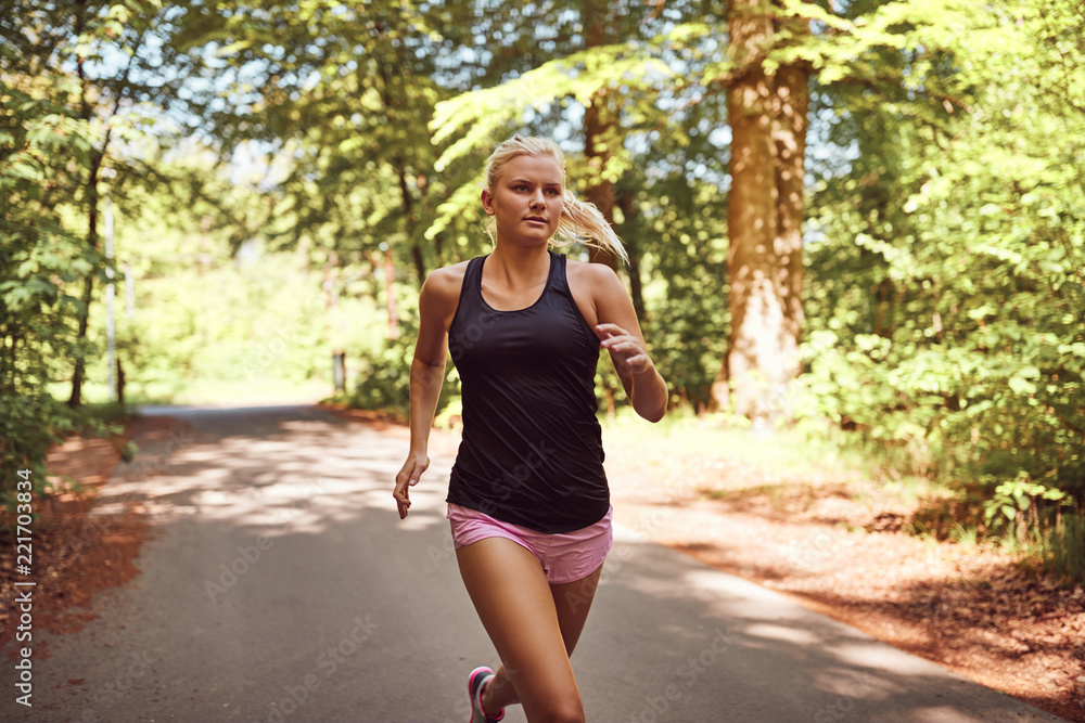 Fit young woman jogging alone on a forest path Fit young woman jogging alone on a forest path