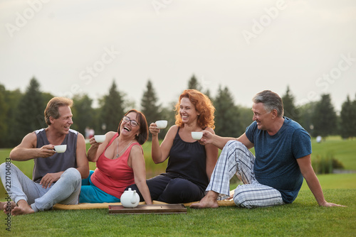 Outdoor tea party. Happy cheerful mature people.