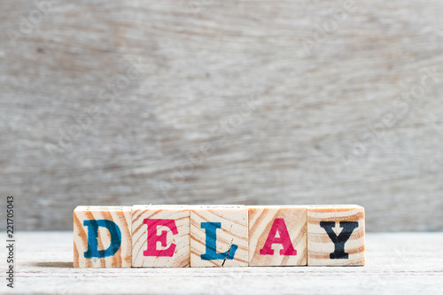 Letter block in word delay on wood background