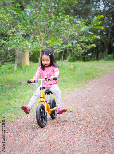 Little girl learns to riding balance bike on slope in the park