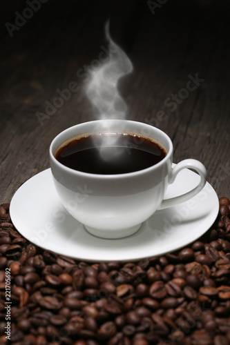 Cup of coffee with steam and coffee beans