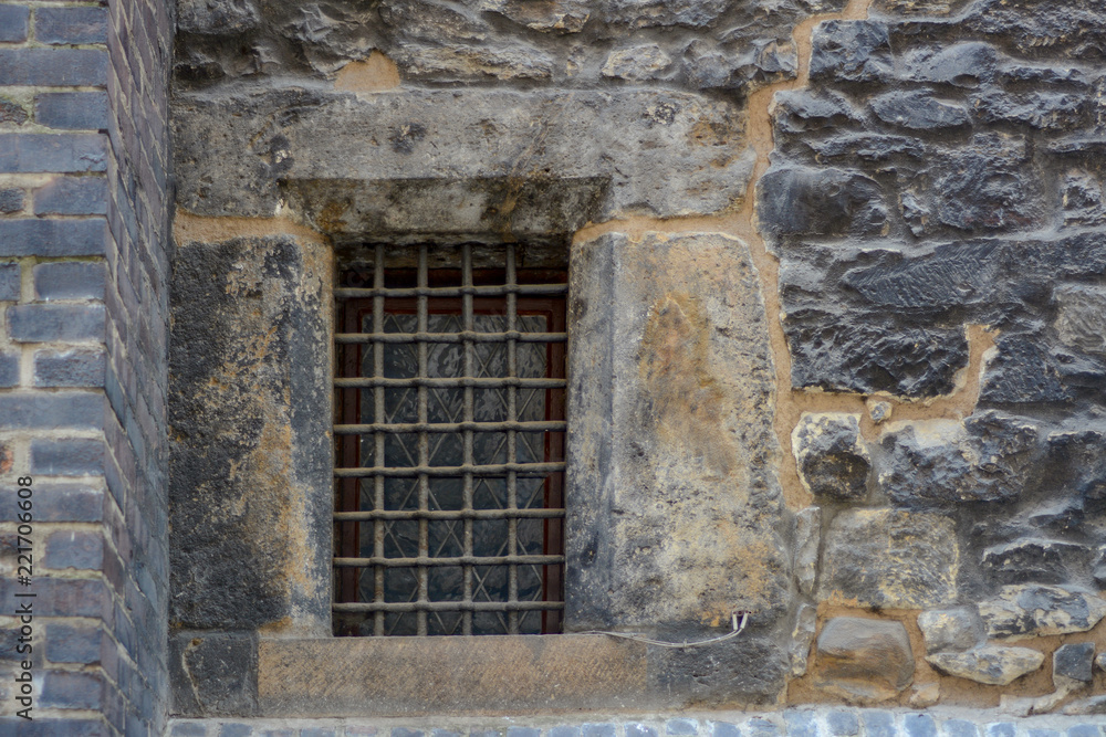 The old wall of stone blocks with a lattice window