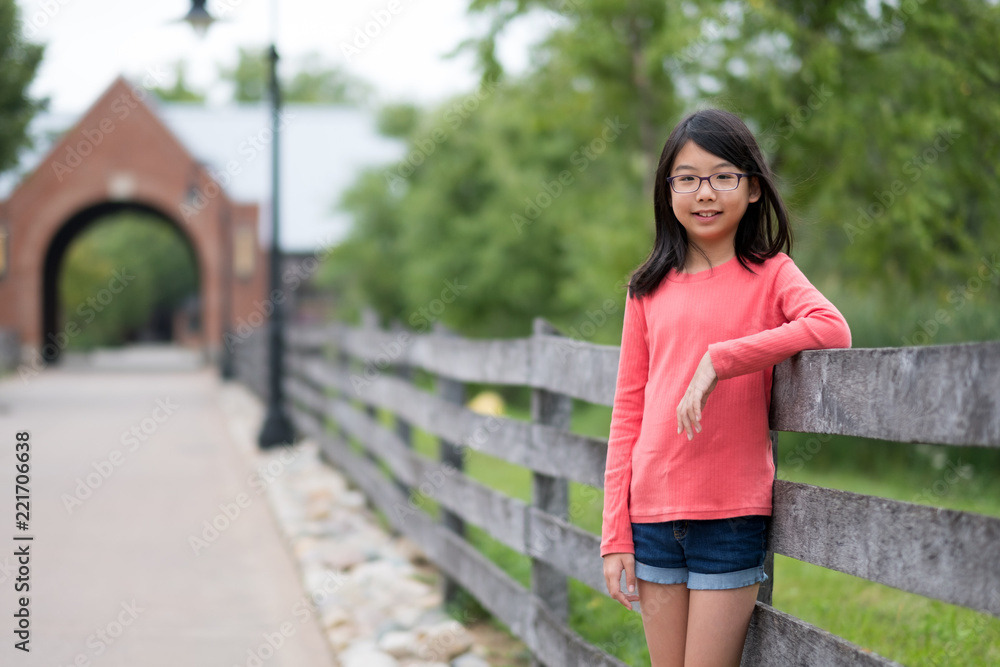 Smiling little Asian girl standing in the outdoor park Smiling little Asian girl standing in the outdoor park
