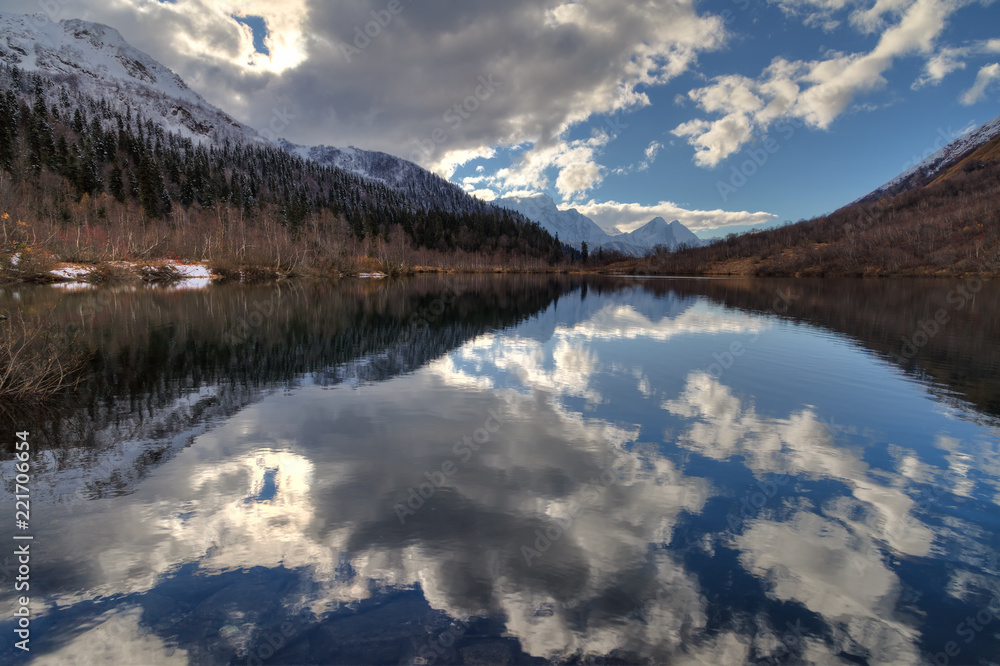 Kardyvach mountain lake with sky reflections. Scenic dramatic autumn sunset landscape. Sochi, Russia, Caucasus mountains