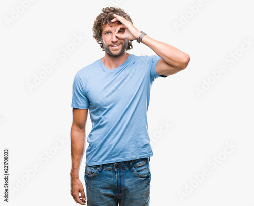 Handsome hispanic model man over isolated background doing ok gesture with hand smiling, eye looking through fingers with happy face. © Krakenimages.com
