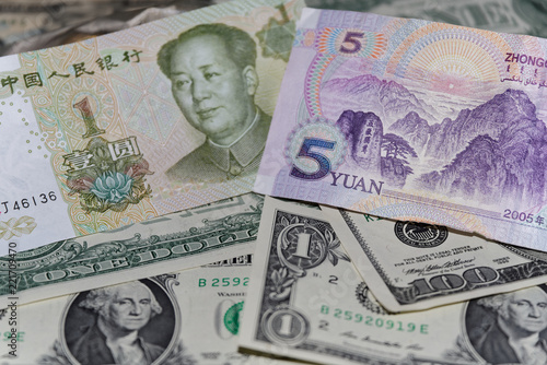 Banknote of five Chinese yuan against background of american dollars