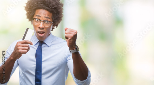 Afro american man holding credit card over isolated background annoyed and frustrated shouting with anger, crazy and yelling with raised hand, anger concept