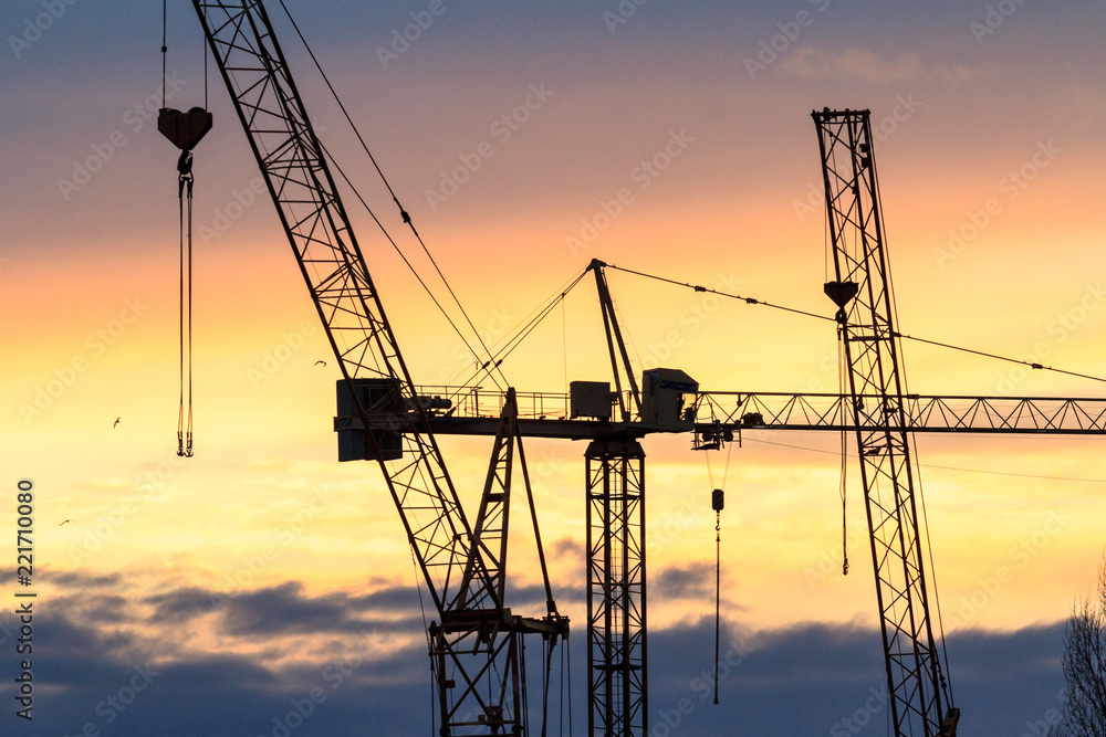 Industrial background with silhouette of construction crane at sunset