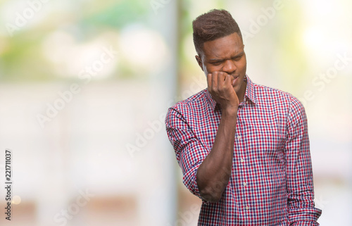 Young african american man over isolated background looking stressed and nervous with hands on mouth biting nails. Anxiety problem.