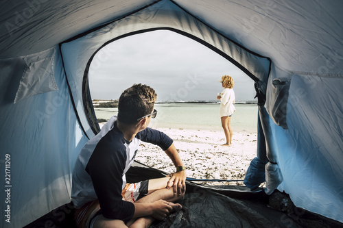 Alternative vacation enjoying total freedom with tent camped on the white sandy beach and blue ocean and sky. couple of caucasian people enjoying the world in wanderlust. summer holiday and enjoy 