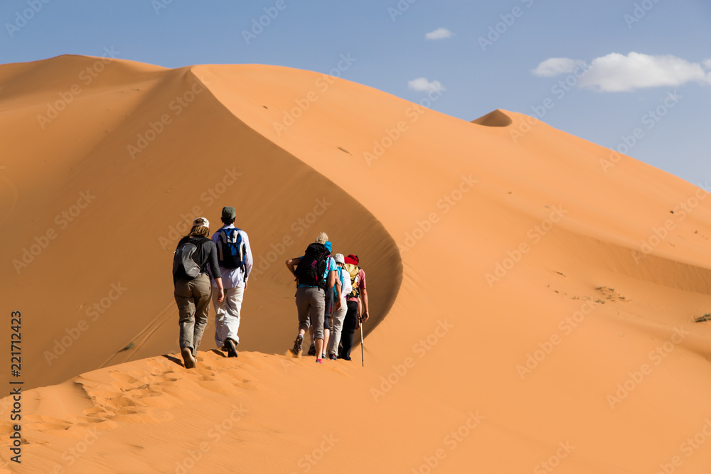 Group of people climbing sand dunes