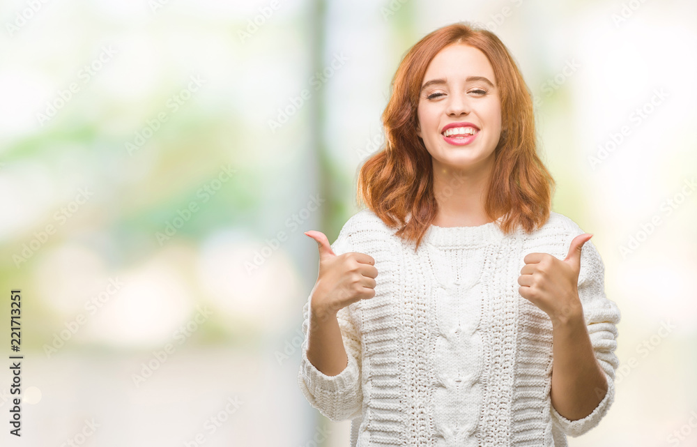 Young beautiful woman over isolated background wearing winter sweater success sign doing positive gesture with hand, thumbs up smiling and happy. Looking at the camera with cheerful expression Young beautiful woman over isolated background wearing winter sweater success sign doing positive gesture with hand, thumbs up smiling and happy. Looking at the camera with cheerful expression