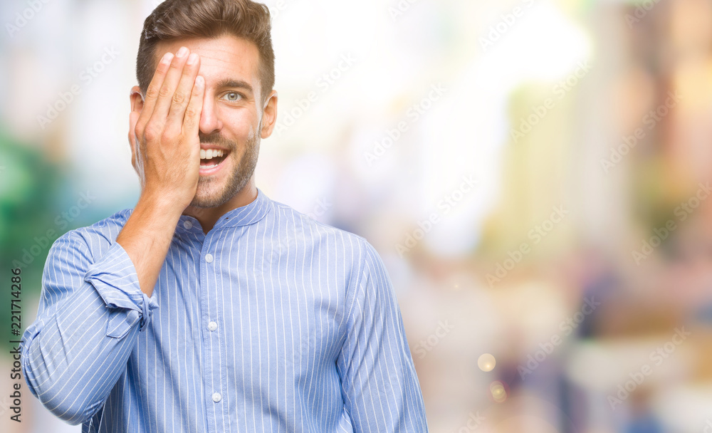 Obraz premium Young handsome man over isolated background covering one eye with hand with confident smile on face and surprise emotion.