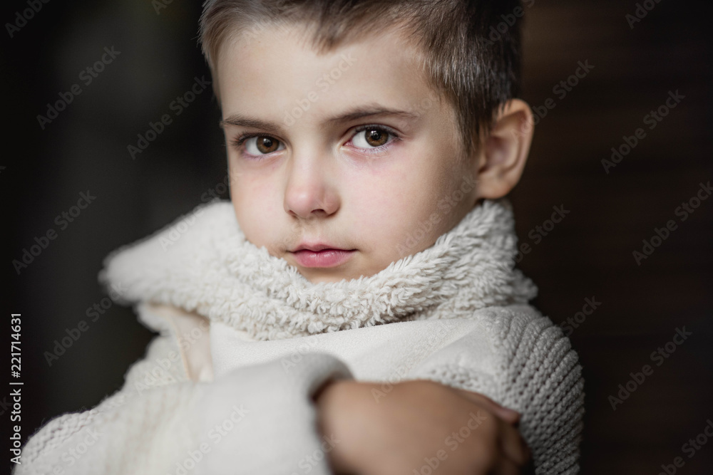 A young boy, a serious look is dressed in a knitted white sweater. Portrait A young boy, a serious look is dressed in a knitted white sweater. Portrait
