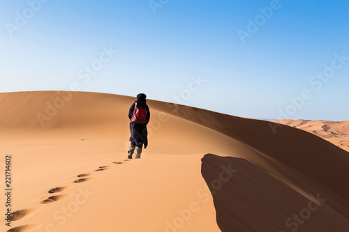 One male tuareg climbing a dune in the desert.