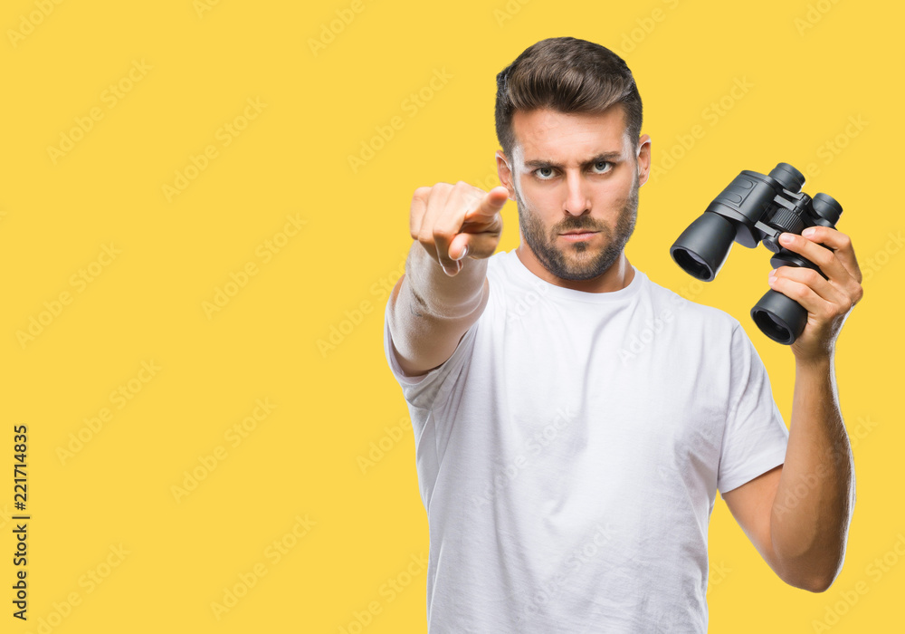 Young handsome man looking through binoculars over isolated background pointing with finger to the camera and to you, hand sign, positive and confident gesture from the front Young handsome man looking through binoculars over isolated background pointing with finger to the camera and to you, hand sign, positive and confident gesture from the front