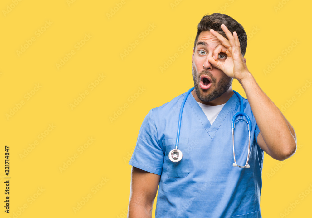 Young handsome doctor surgeon man over isolated background doing ok gesture shocked with surprised face, eye looking through fingers. Unbelieving expression. Young handsome doctor surgeon man over isolated background doing ok gesture shocked with surprised face, eye looking through fingers. Unbelieving expression.