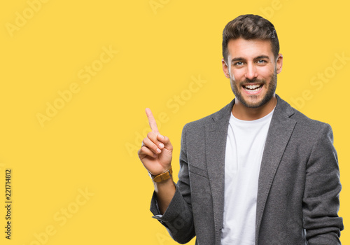 Young handsome business man over isolated background with a big smile on face, pointing with hand and finger to the side looking at the camera.