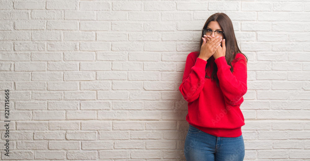 Young brunette woman standing over white brick wall shocked covering mouth with hands for mistake. Secret concept. Young brunette woman standing over white brick wall shocked covering mouth with hands for mistake. Secret concept.