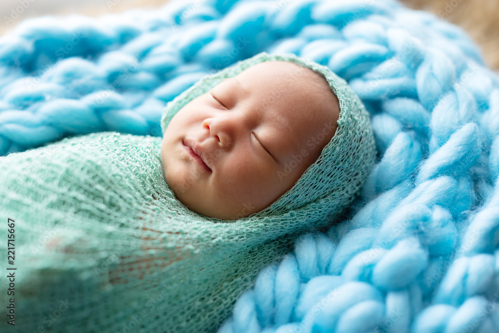 Cute little newborn girl lying on blue furry blanket wearing pastel