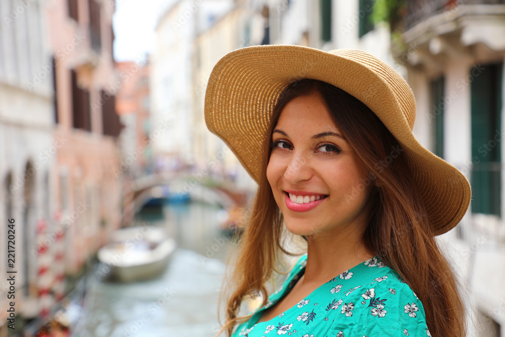 Fototapeta premium Portret uśmiechniętej wesołej kobiety w kapeluszu i zielonej sukience podczas weneckich wakacji. Szczęśliwy atrakcyjny uśmiech dziewczyny do kamery w Wenecji, Włochy.