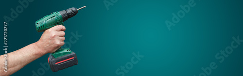 Hand with electric drill on green background