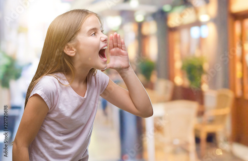 Young beautiful girl over isolated background shouting and screaming loud to side with hand on mouth. Communication concept.