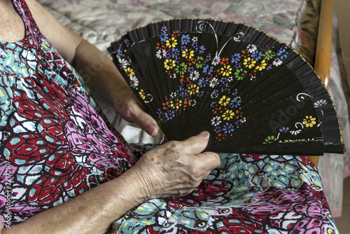 Cuadro en lienzo Mujer de la tercera edad aliviando el calor con un abanico.
